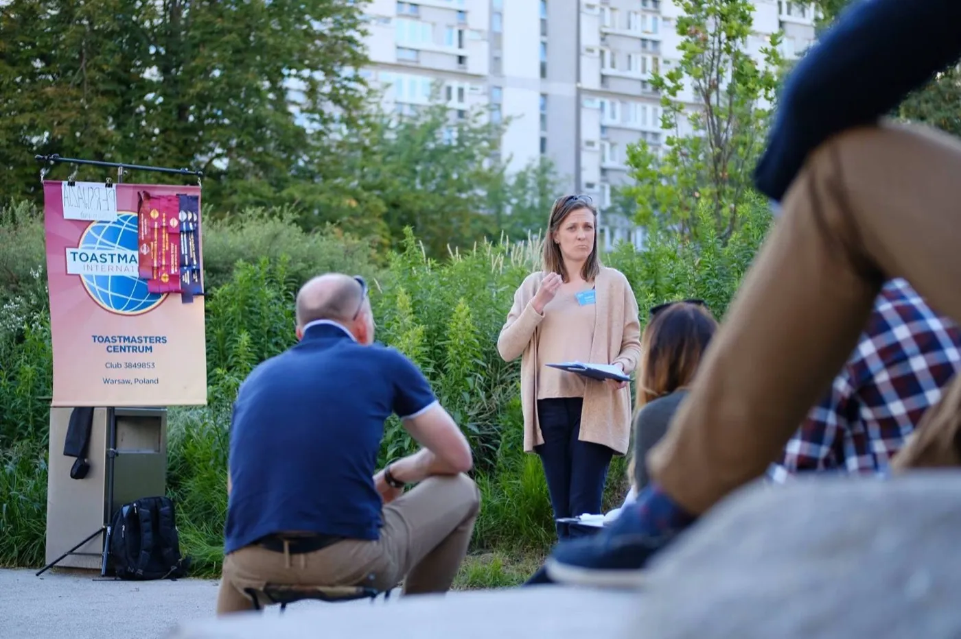 Mówca przy banerze Toastmasters Centrum podczas spotkania w plenerze